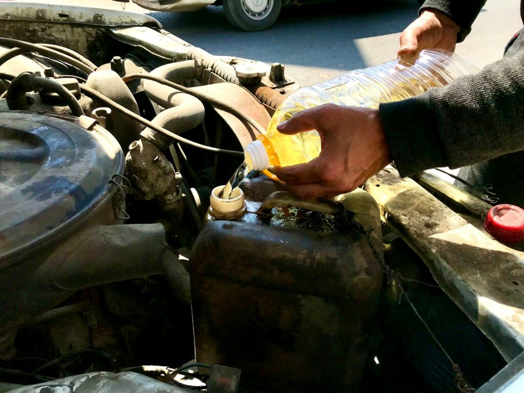 average oil change cost 2026 showing a mechanic checking engine oil under a car hood representing oil change prices by shop and car brand