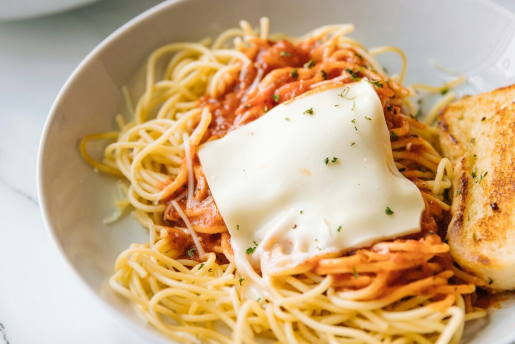 Italian-American dishes showing a plate of spaghetti and meatballs with garlic bread and chicken parmesan representing the most popular Italian-American foods that were invented in the United States not Italy