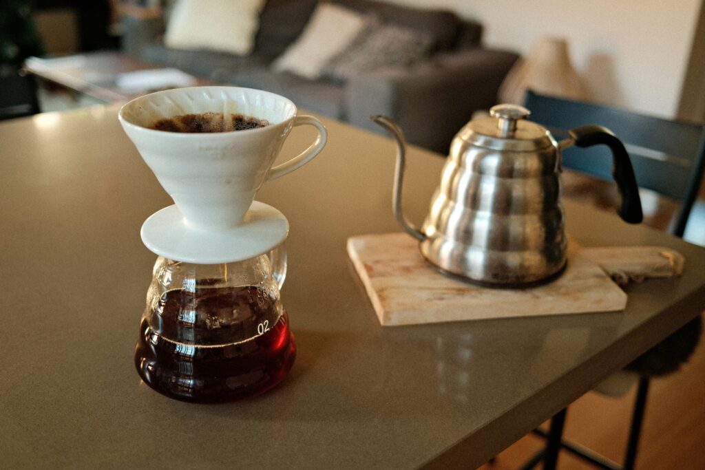 best pour over coffee maker showing Hario V60 dripper and Chemex on a wooden counter with gooseneck kettle and freshly brewed pour over coffee