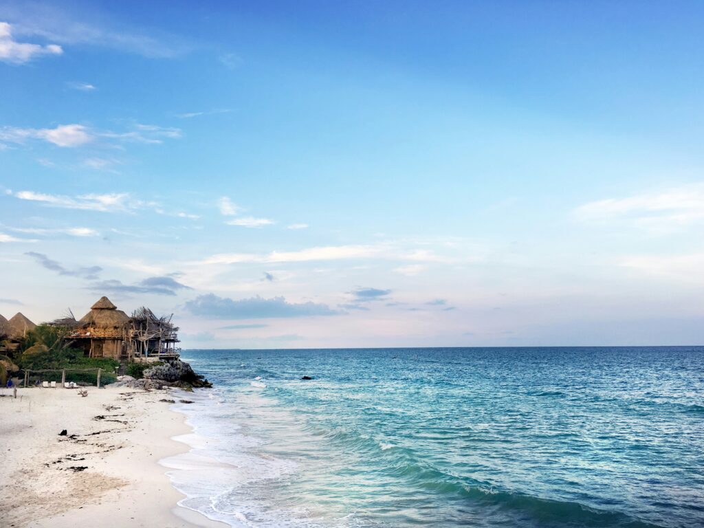 luxury destinations mexico showing infinity pool overlooking turquoise Caribbean water at a five-star resort on the Riviera Maya with white sand beach beyond
