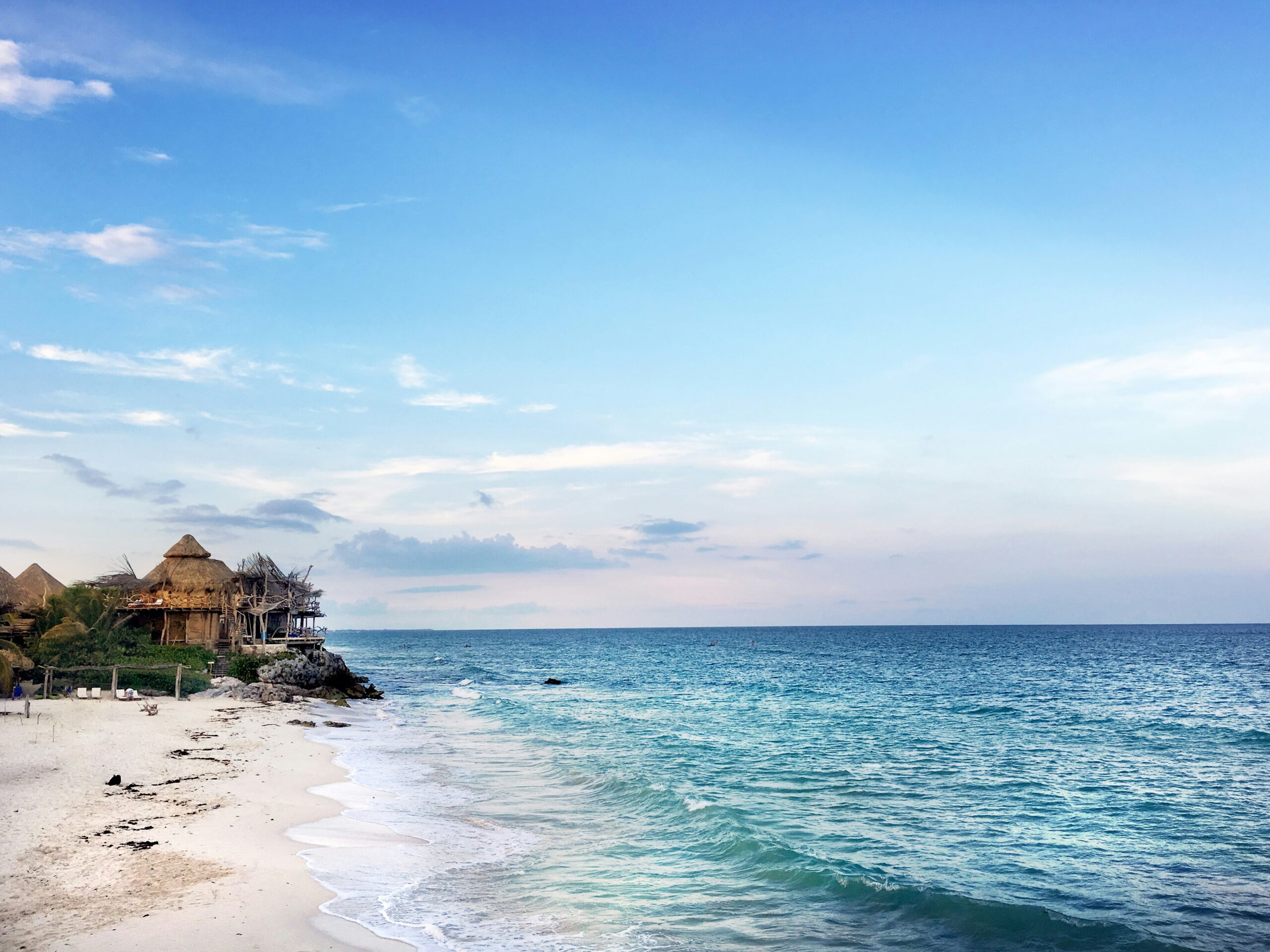 luxury destinations mexico showing infinity pool overlooking turquoise Caribbean water at a five-star resort on the Riviera Maya with white sand beach beyond