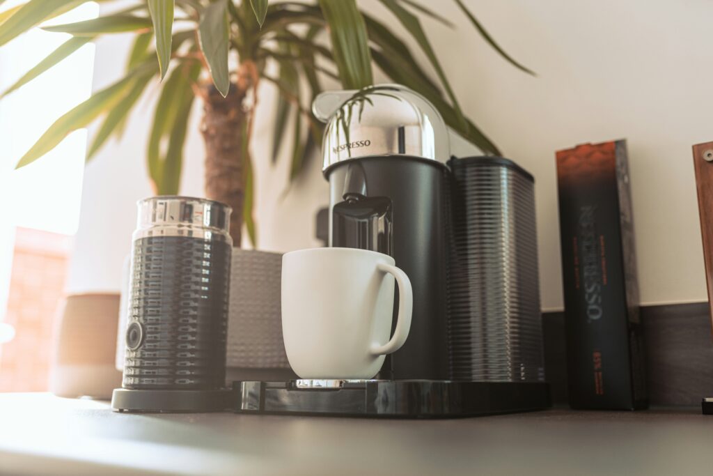 best nespresso machine showing Nespresso VertuoPlus and Essenza Mini side by side with coffee capsules on a kitchen counter representing the Original and Vertuo line comparison