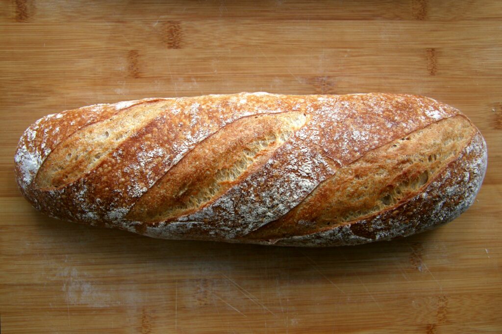 artisan bread recipe showing two freshly baked homemade artisan loaves with golden crusts on a wooden board representing easy homemade artisan bread made without a bread machine